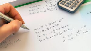 Pessoa estudando matemática financeira com gráficos e fórmulas, representando a importância do aprendizado de conceitos como juros simples e compostos para uma gestão financeira eficaz.